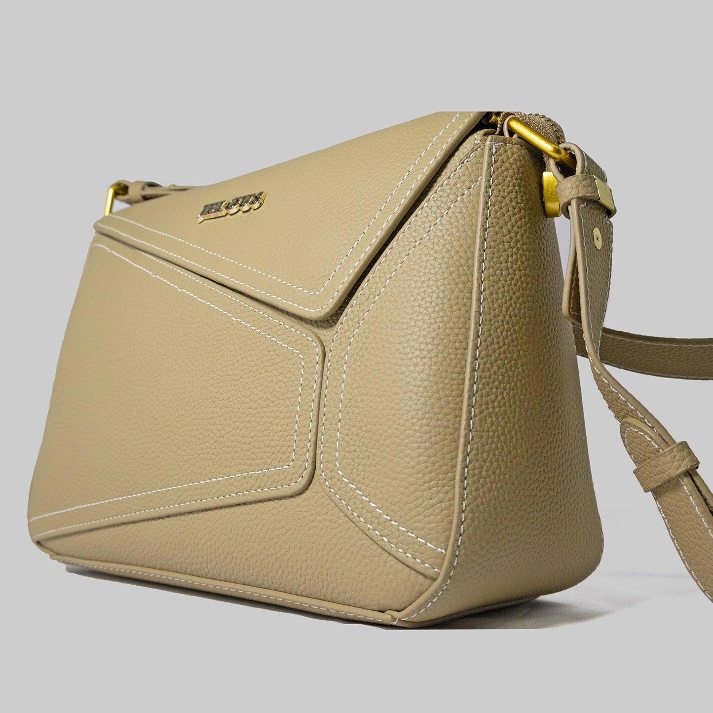 Beige genuine cowhide leather handbag named The Jelous Astra with a geometric front flap, magnetic closure, and two detachable straps.