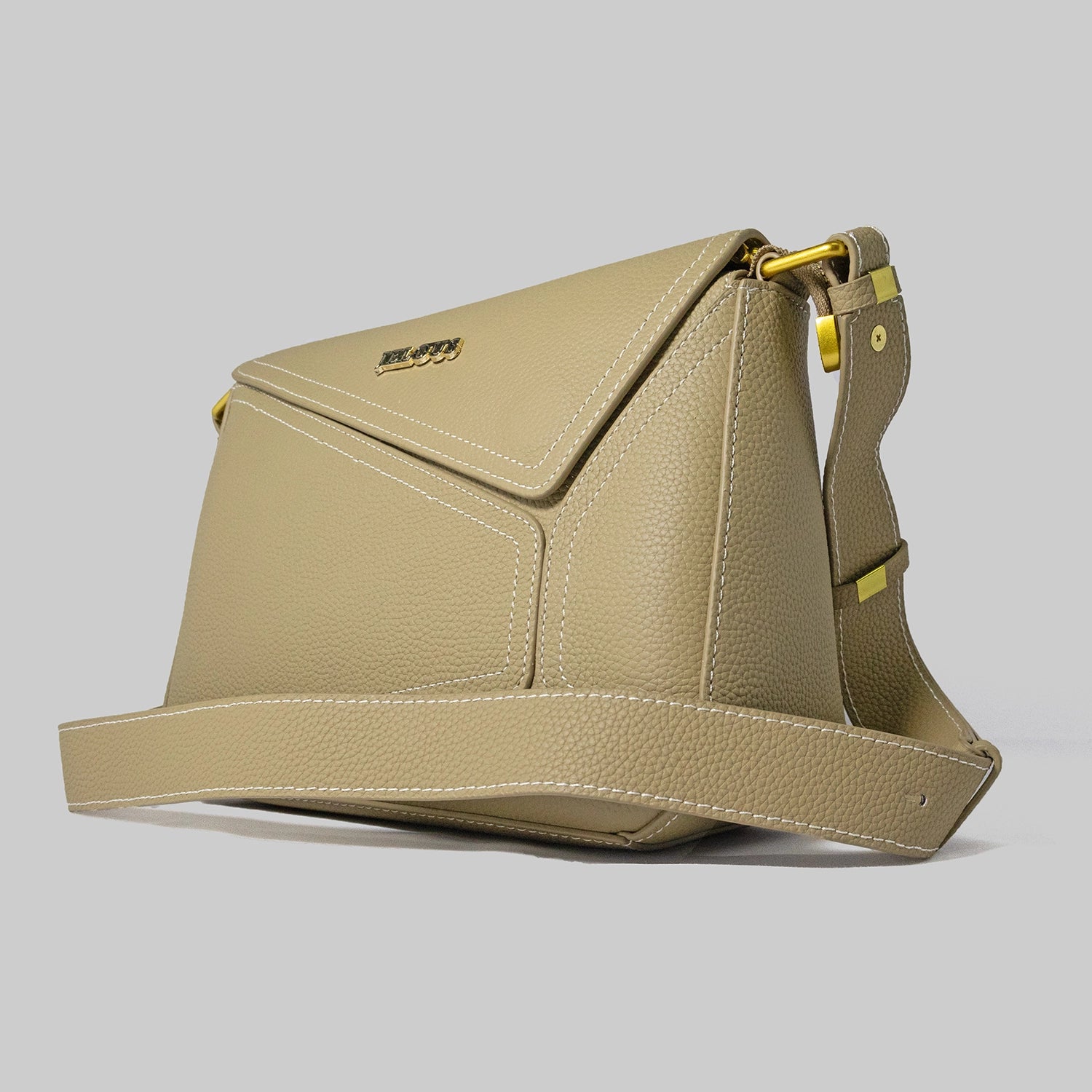 Beige genuine cowhide leather handbag named The Jelous Astra with a geometric front flap, magnetic closure, and two detachable straps.