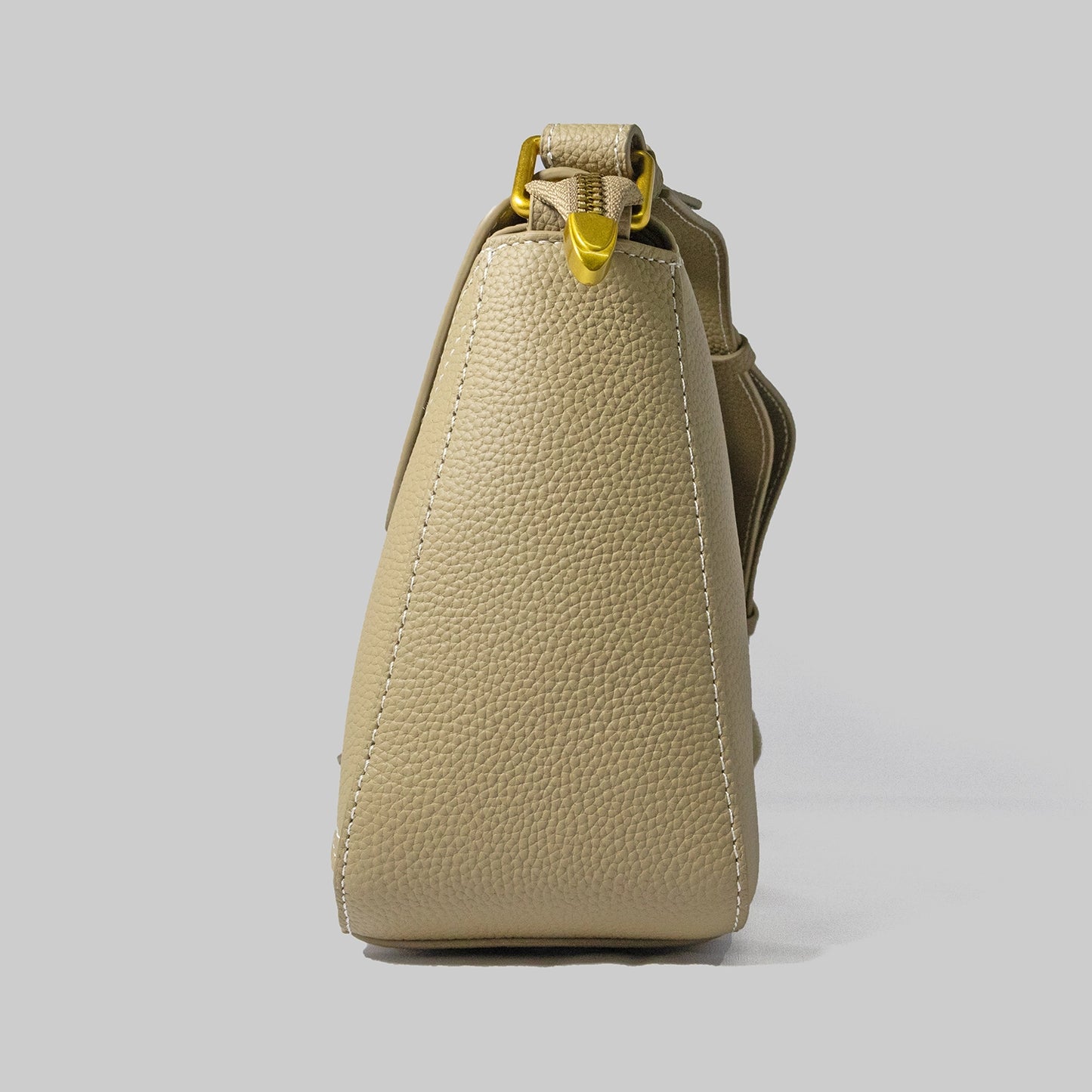 Beige genuine cowhide leather handbag named The Jelous Astra with a geometric front flap, magnetic closure, and two detachable straps.
